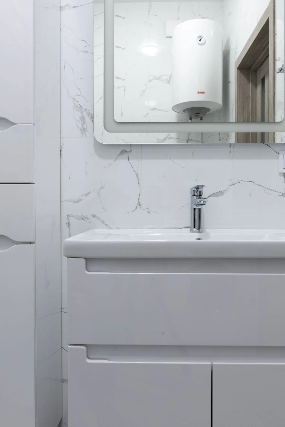 Wall-mounted hot water tank reflected in a bathroom mirror above a sink