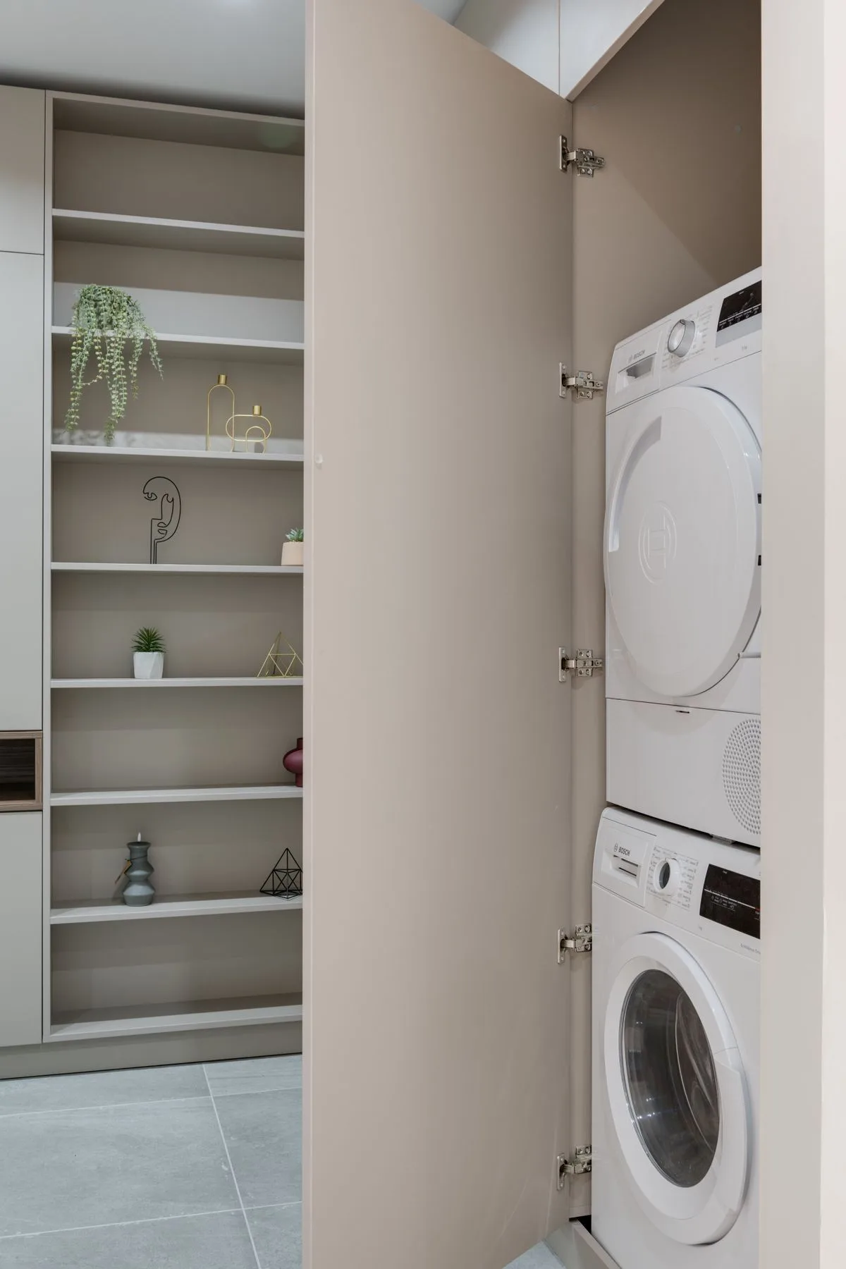 Stacked washer and dryer tucked behind cabinet doors in a tight closet