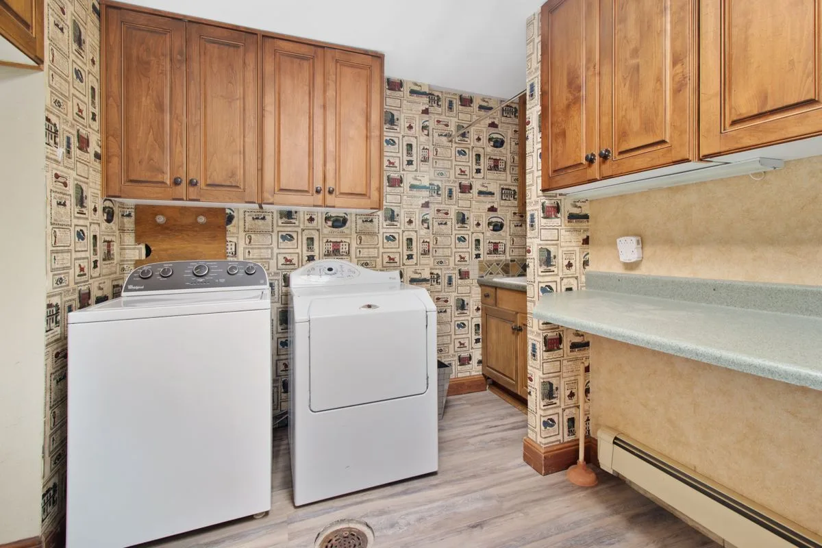 Laundry room with a top-load washer and dryer and a visible floor drain in the tile