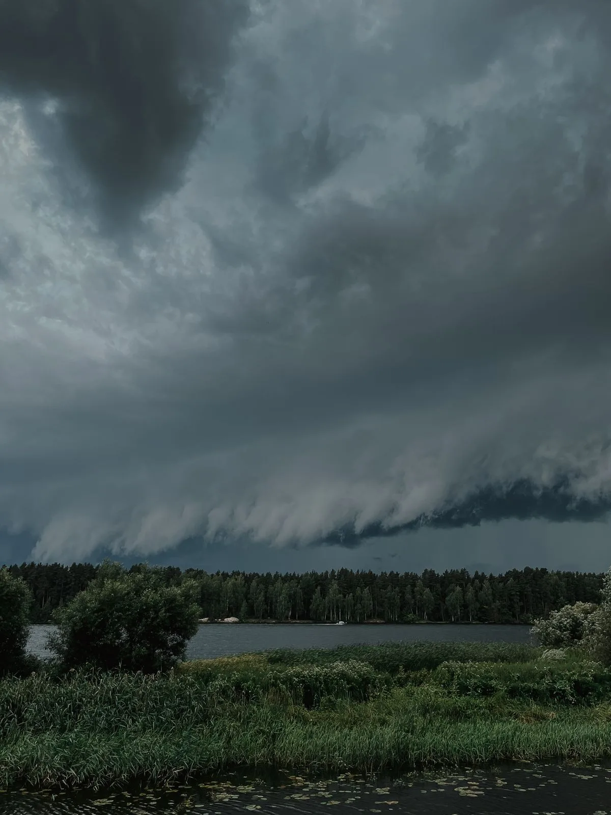 Dark storm clouds gathering over a lake before a severe storm