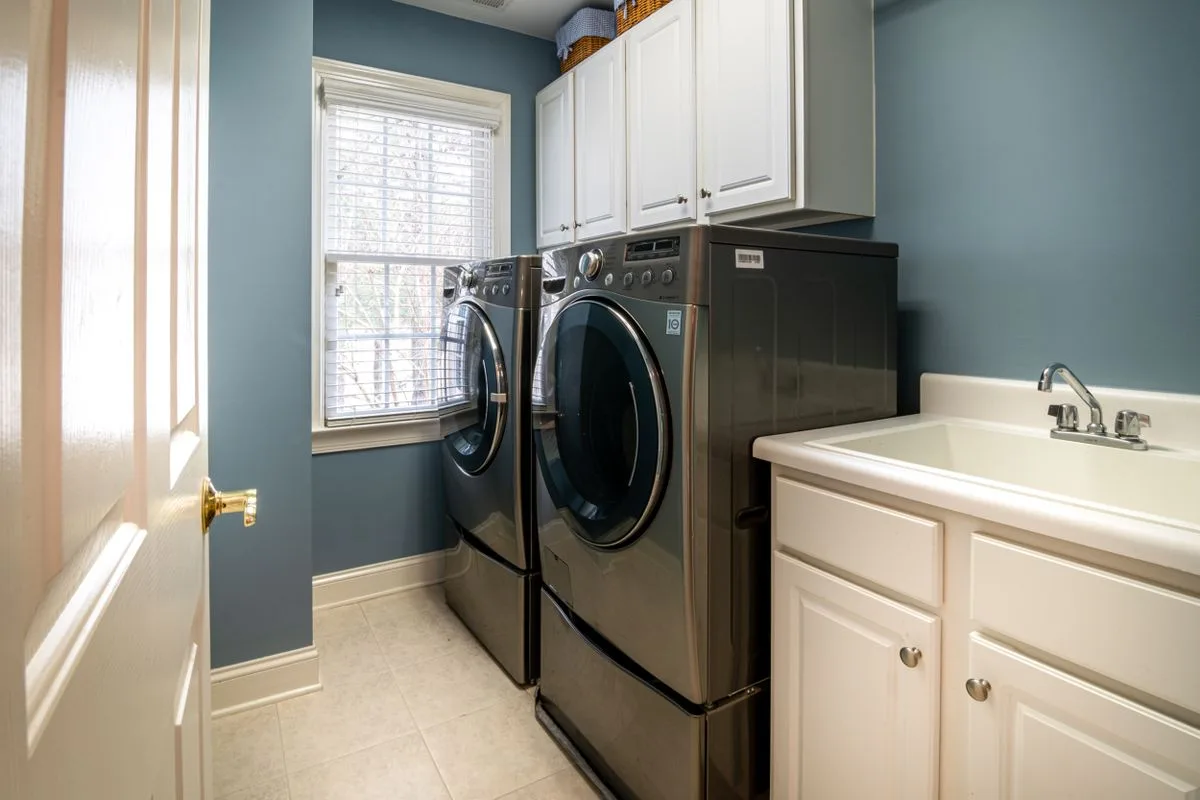 Bright laundry room with a washer, dryer, utility sink and cabinets