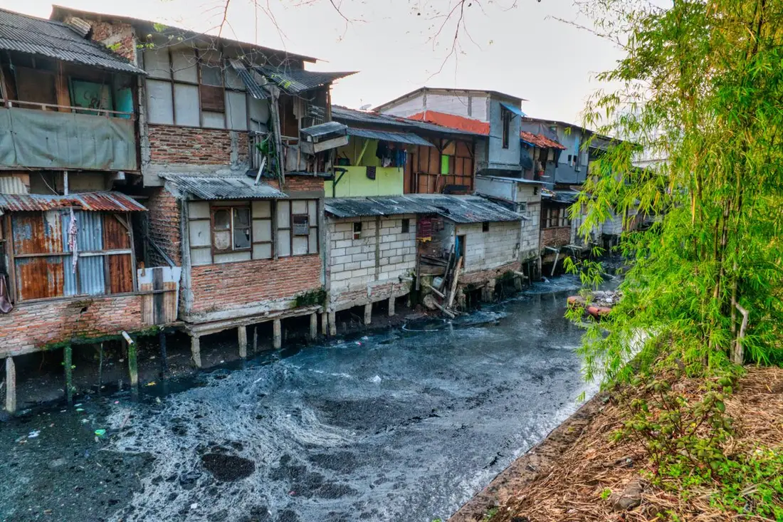 Dark contaminated water flowing past riverside homes