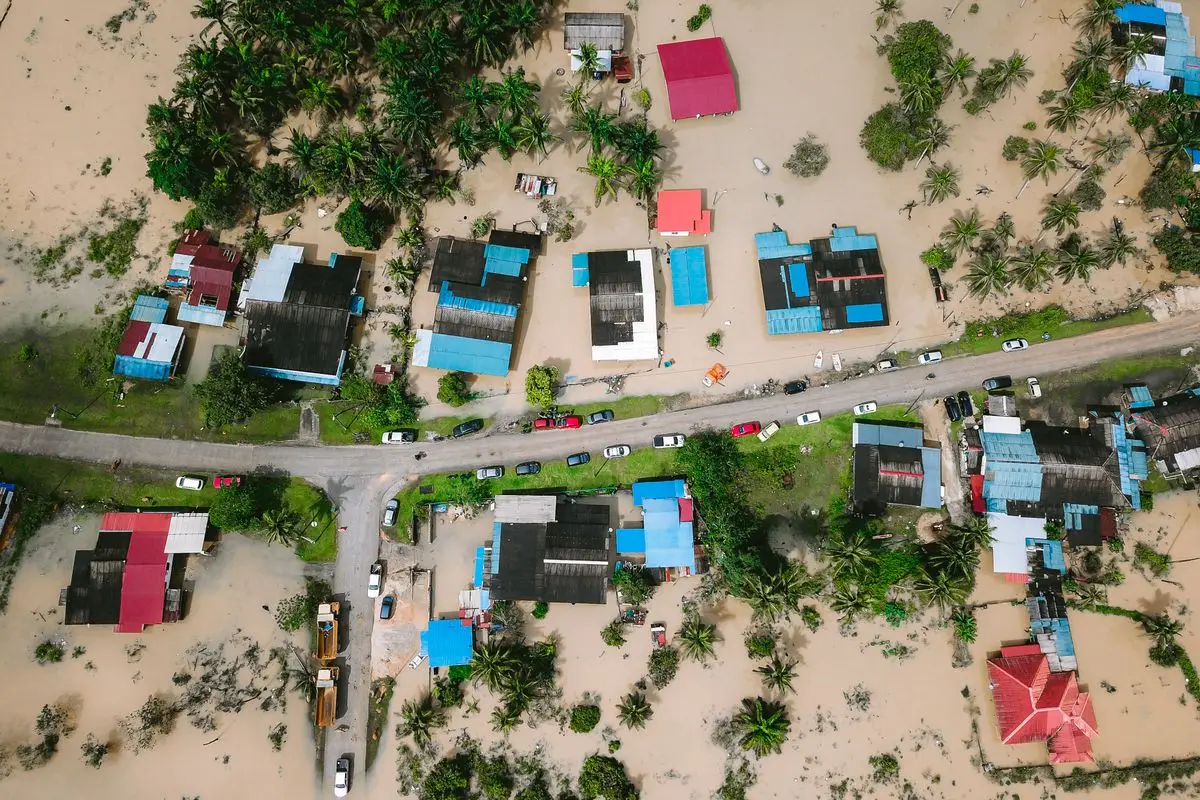Aerial view of a flooded village with homes surrounded by muddy floodwater