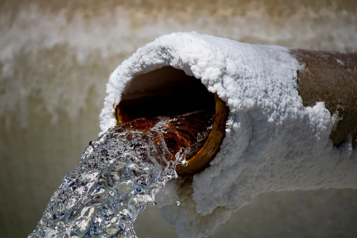 Ice-covered pipe bursting and pouring water after a Texas hard freeze