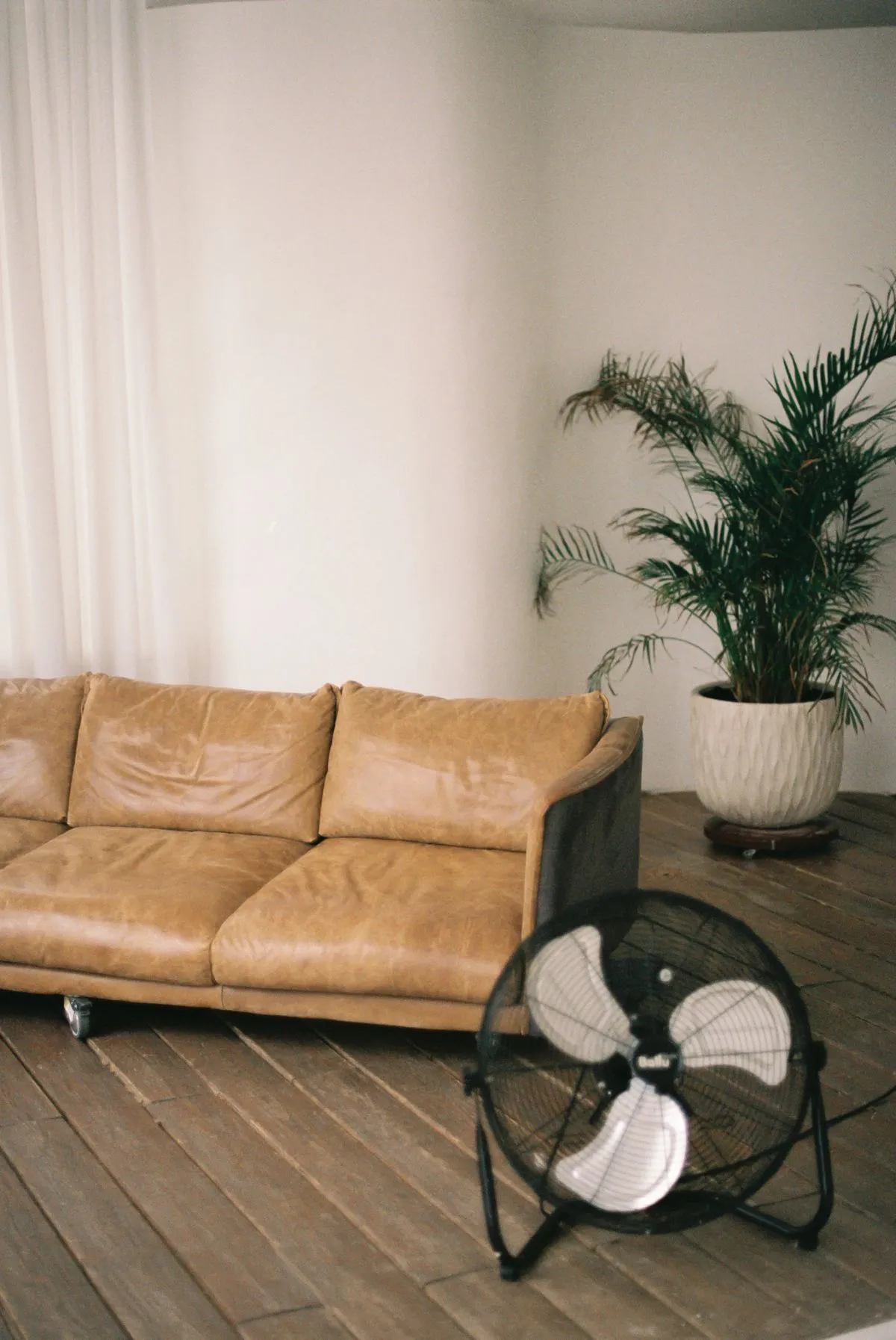 Floor fan drying a living room with a leather sofa after water damage
