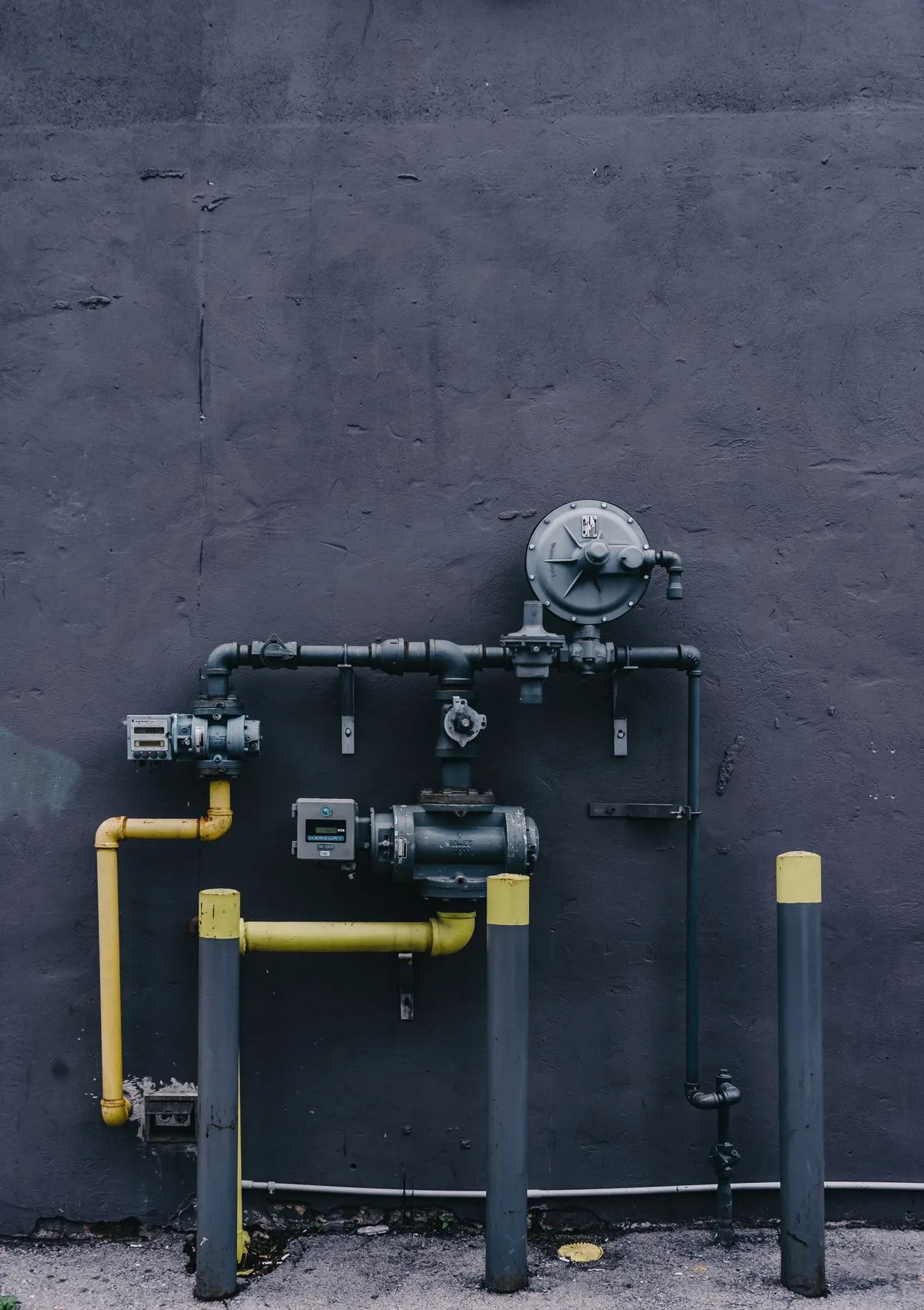 Pipes and pressure meter on an exterior wall, vulnerable to hard freezes